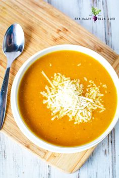 a white bowl filled with soup on top of a wooden cutting board