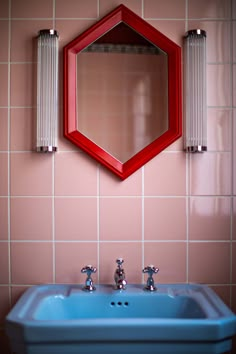 a blue sink sitting under a mirror in a bathroom next to a wall mounted faucet