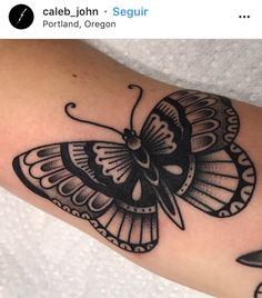 a black and white butterfly tattoo on the arm