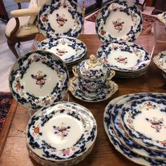 a table topped with lots of blue and white china dishes on top of a wooden table