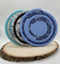 three blue and white plates sitting on top of a wooden slice