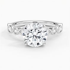 a white gold engagement ring with an oval cut diamond in the center and side stones