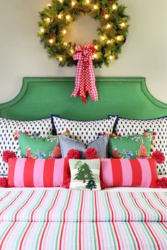 a christmas wreath hangs above the headboard of a bed with colorful pillows and throw pillows