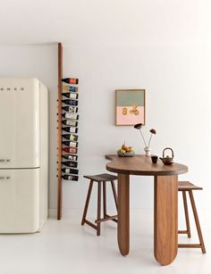 a white refrigerator freezer sitting next to a table with two stools in front of it