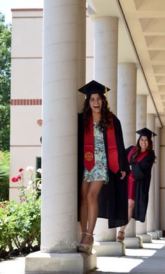 two girls in graduation gowns are standing on the steps