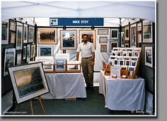 a man standing in front of a booth with many pictures on the walls and tables