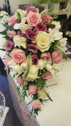 a bouquet of pink and white flowers sitting on top of a table in a room