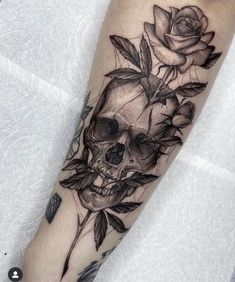 a skull and roses tattoo on the arm is shown in black and grey ink,