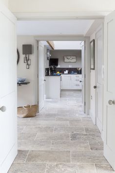 an open hallway leading to a kitchen with white cabinets and counter tops on either side