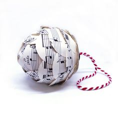 an origami ball with sheet music notes on it and a red string attached to it