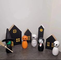 halloween decorations are arranged on a table in front of a white wall and black houses