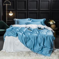 a bed with blue and white sheets in a room next to a green chair on the floor