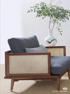 a white vase sitting on top of a wooden table next to a chair with gray cushions