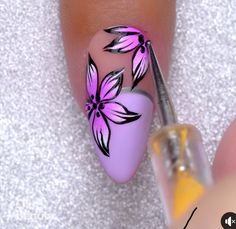 the nail is being painted with purple flowers