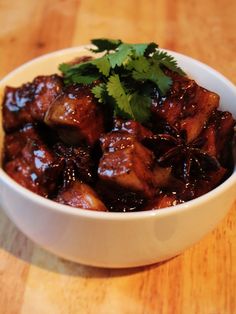 a white bowl filled with meat and garnished with cilantro on top