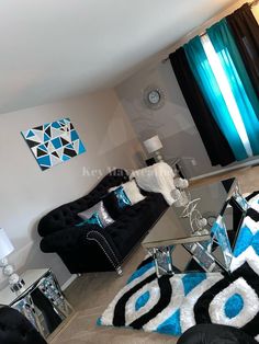 a living room filled with black and white furniture next to a blue curtained window