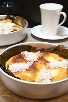 some food is sitting in a pan on a table next to cups and saucers