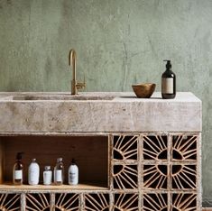 a bathroom sink sitting next to a wooden cabinet with bottles on it and a soap dispenser