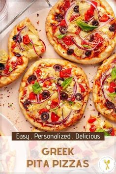 four personalized pizzas with various toppings sitting on a plate next to wine glasses and utensils