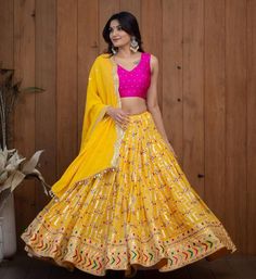 This stunning A-line yellow georgette lehenga set features intricate floral thread embroidery for a feminine look. It comes with a semi-stitched lehenga along with an exquisite pink silk blouse decorated with beautiful embroidered accents. The look is completed with a yellow georgette dupatta that has eye-catching embroidered details.  #yellowlehenga #yellowlehengas #yellowlehengacholi #yellowlehengadress #yellowlehengadesigns #yellowcolorlehenga Lehenga Choli Designs, Indian Wedding Lehenga, Reception Lehenga, Yellow Lehenga, Bollywood Lehenga, Lengha Choli, Indian Wedding Wear, Indian Lehenga