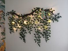 a branch with lights hanging from it on the wall