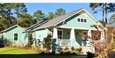 a small blue house in the middle of a yard with trees and shrubs around it