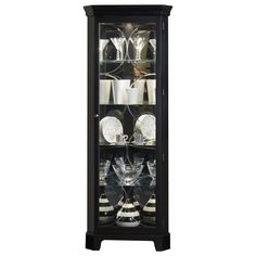 a black glass door cabinet filled with dishes and wine glasses on top of each shelf