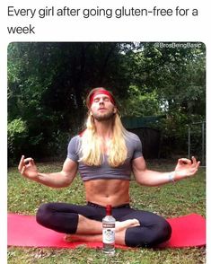 a man sitting on top of a red yoga mat in the middle of a park