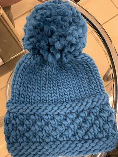 a blue knitted beanie sitting on top of a glass table next to a mirror