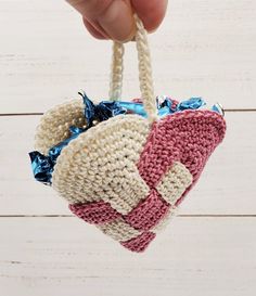 a hand holding a crocheted heart ornament