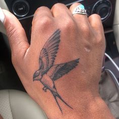 a person with a bird tattoo on their arm and wrist, driving in a car