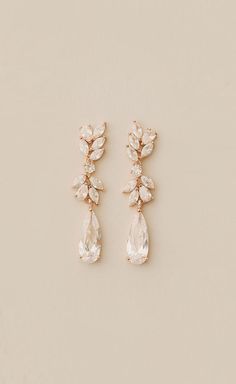 two pairs of earrings with white stones and crystal drops on the bottom, one in gold