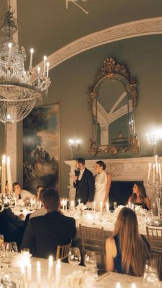 a bride and groom standing at the end of their wedding reception in front of an ornate chandelier