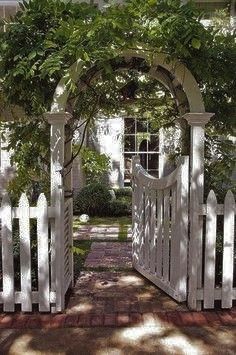 a white picket fence with an arch over it