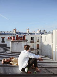 a man sitting on top of a roof next to a woman