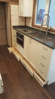 a kitchen with an oven, sink and cabinets in the corner next to a window