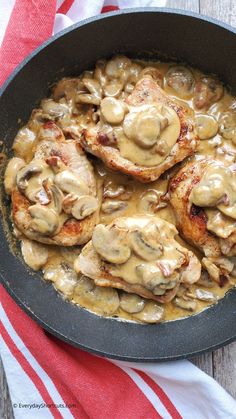 chicken with mushroom gravy in a skillet on a red and white towel