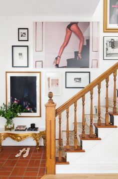 a staircase with pictures on the wall and shoes on the floor in front of it