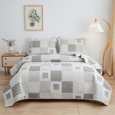 a bedroom with a bed covered in a white and grey quilt