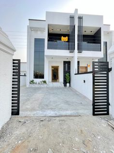 a white house with black iron gates on the front and side doors that lead into it