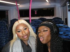 two women sitting on a bus with headphones on and one is sticking out her tongue