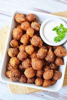 a white bowl filled with tater tots next to a small bowl of ranch dressing