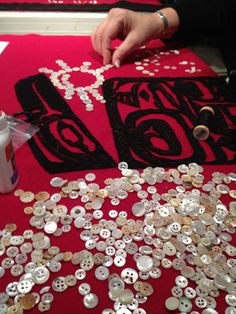 a person is making buttons on a red table