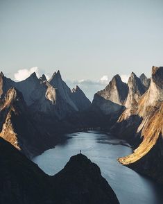 a lake surrounded by mountains in the middle of it's own land, with a person standing on top