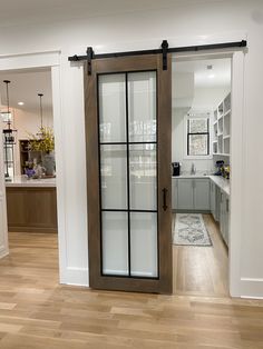 an open kitchen and living room with sliding glass doors on the front door, hardwood flooring and white walls