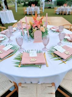 the table is set with pink napkins and place settings for guests to sit at