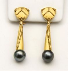 "Stunning one-of-a-kind 22k yellow gold and Tahitian Pearl dangle earrings hand-fabricated by master jeweler Stewart Jones. Earrings are composed of an upper shield-shaped section that is approx 14mm in size and a lower finial-like piece that is approx. 24mm long, with a Tahitian Cultured Pearl at its terminus. The pearls are each just over 10mm in diameter and are black with silvery-gray and bluish overtones. They have a medium luster and are noticeably blemished with some pitting, but this doe Tahitian Pearl Earrings, Oyster Pearl, Pearl Dangle Earrings, Tahitian Pearls, Pearl Earrings Dangle, Stone Design, Ear Jewelry, 22k Gold, Gold Jewellery