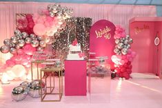 a pink and silver birthday party with balloons, cake table and decorations on the wall