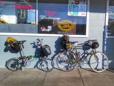 three bikes parked next to each other in front of a bike shop with bags hanging on the wall