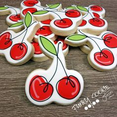 cookies decorated with cherries and green leaves are on a table next to each other